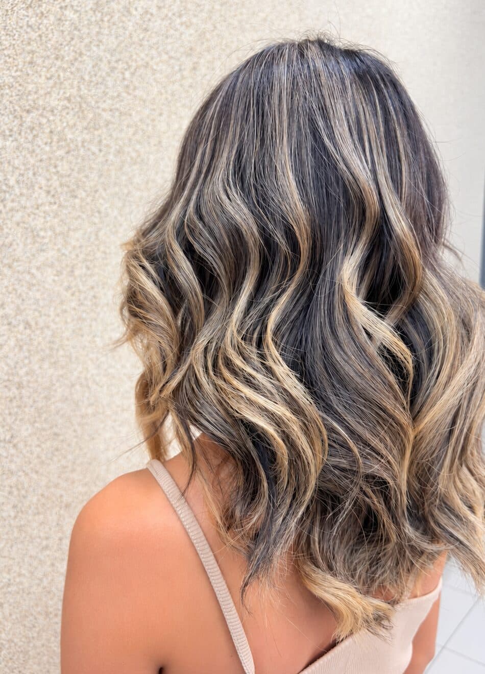 Dark brown hair with honey-toned highlights and soft waves, done by the Hair & Hands team
